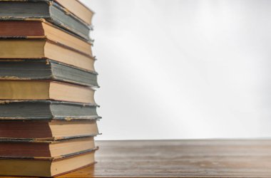 ahşap masa üzerinde ciltli kitap yığını