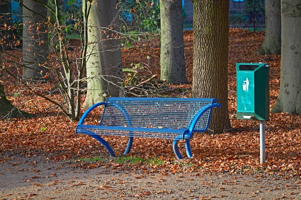 Mavi park bankında yeşil çöp tenekesi ile