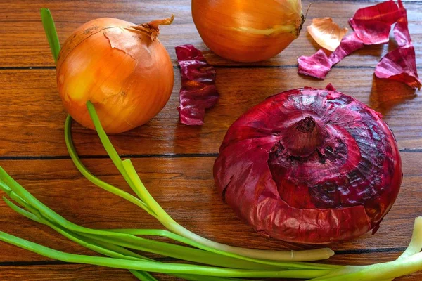 On the background of boards three types of onions: onion, leek a — Stock Photo, Image