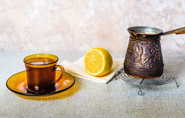 Una tazza di caffè, un limone e acqua bollente sul tavolo della cucina . — Foto Stock