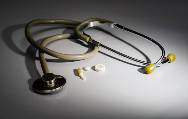 Стетоскоп по генеральному плану, в центре таблетки и колпачка
