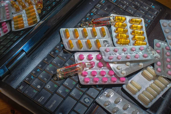 On the computer keyboard are pills of a different color, capsule — Stock Photo, Image