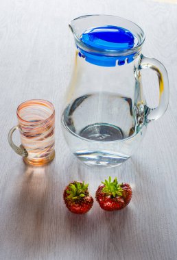 Sürahi, bardak su ve iki çilek.
