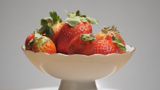 用红色的 多汁的草莓和中性的灰色背景旋转着的白色花瓶 — 图库视频影像