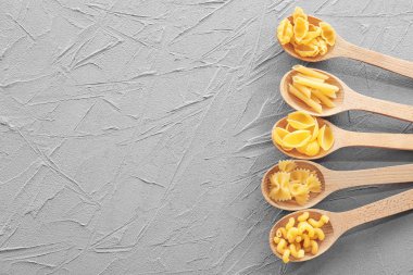 Tahta kaşıklar gri tablo farklı pişmemiş makarna ile