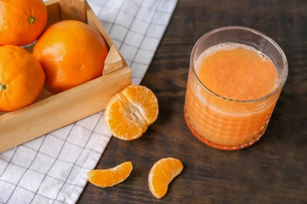 Стекло с вкусным цитрусовым соком и свежими мандаринами на столе — стоковое фото