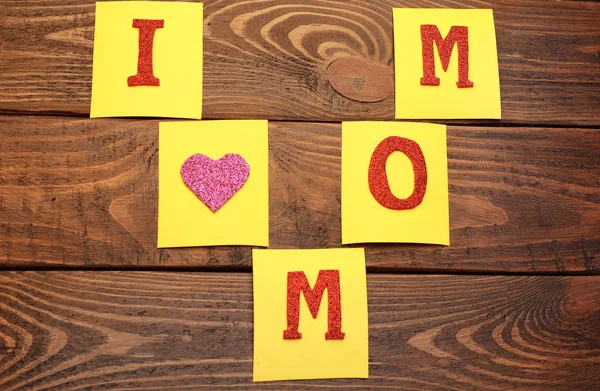 Phrase ich liebe Mama aus klebrigen Zetteln auf hölzernem Hintergrund. Grüße zum Muttertag — Stockfoto