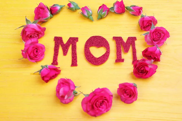Hart vorm gemaakt van rozen en woord "Mom" op houten achtergrond — Stockfoto