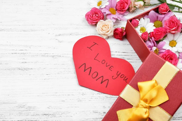 Gåva, blommor och och kort med orden ”Jag älskar dig mamma” på trä bakgrund. Hälsningar för mors dag — Stockfoto