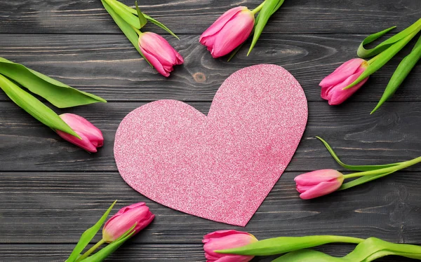 Samenstelling met prachtige tulpen en papier hart op houten achtergrond — Stockfoto