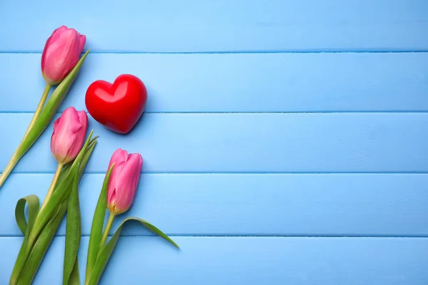 Beautiful tulips and red heart on color wooden background — Stock Photo, Image