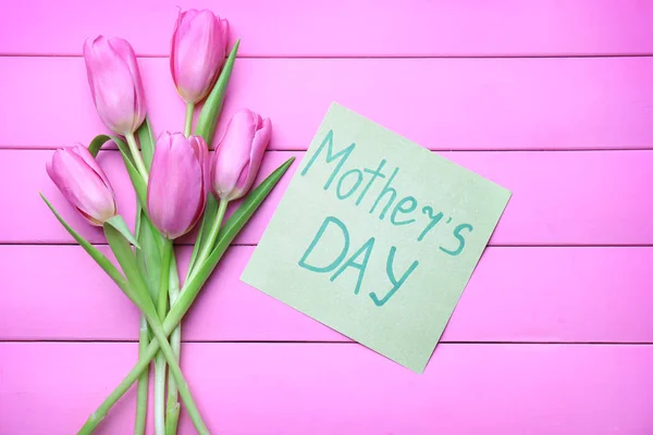 Buquê de belas tulipas e cartão para o Dia das Mães no fundo de cor — Fotografia de Stock