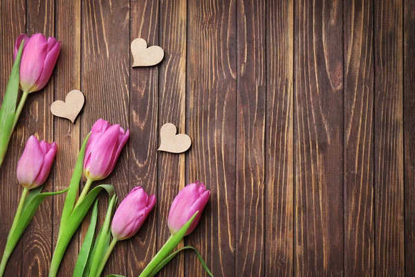 Bei tulipani e piccoli cuori su sfondo di legno — Foto Stock