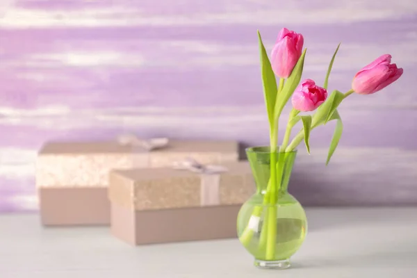 Vas med bukett vackra tulpaner och presentaskar på bordet — Stockfoto