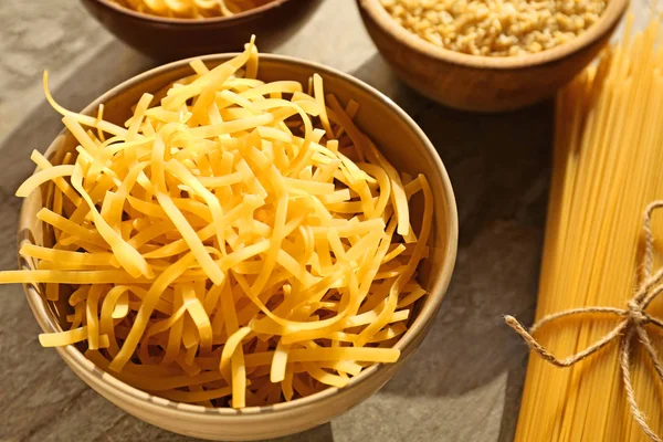 Uncooked pasta in bowl on table — Stock Photo, Image