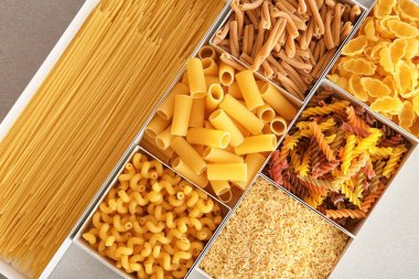 Farklı pişmemiş makarna üzerine açık renkli kutular