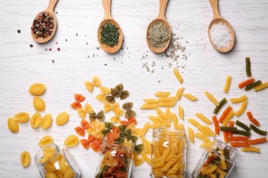 Farklı pişmemiş makarna ve ahşap masa üzerinde baharat kompozisyonu