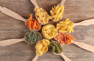 Ahşap masa üzerinde farklı pişmemiş makarna kaşıklarla