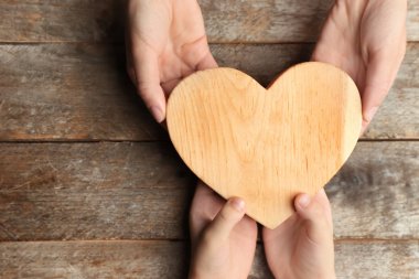 Anne ve çocuk kalp ahşap arka plan üzerinde tutan eller