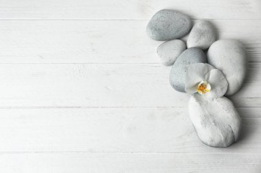 Spa taşlar ve güzel çiçek Beyaz ahşap arka planda, üstten görünüm