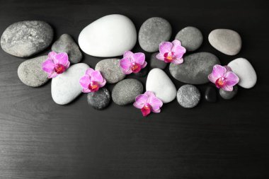 Spa taşlar ve koyu ahşap zemin, üstten görünüm üzerine güzel çiçekler