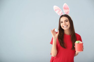 Paskalya yumurtaları ve gri arka plan üzerinde tavşan kulakları olan güzel kadın