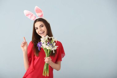 Paskalya bunny kulaklar ve buket çiçek gri arka plan üzerinde olan güzel kadın