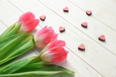 Güzel laleler ve Beyaz ahşap zemin üzerinde küçük dekoratif Kalpler