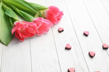 Güzel laleler ve Beyaz ahşap zemin üzerinde küçük dekoratif Kalpler