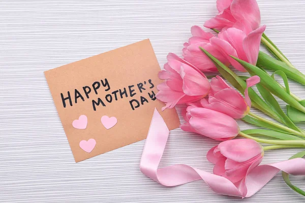 Bouquet of flowers and greeting card for Mother's Day on wooden background — Stock Photo, Image