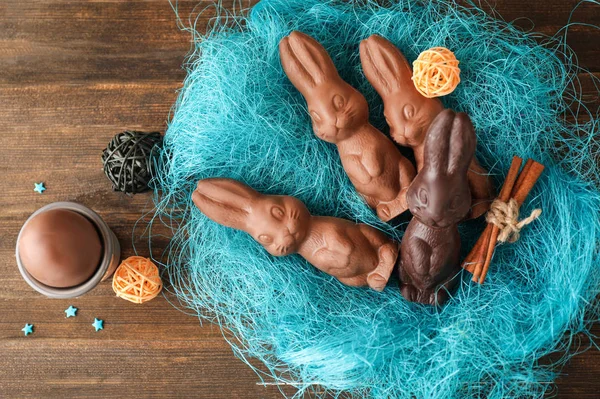 Decorative nest with chocolate Easter bunnies on wooden table — Stock Photo, Image