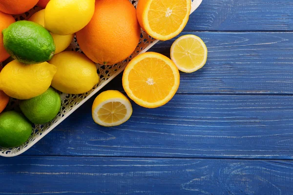 Tray with ripe citrus fruits on wooden background — Stock Photo, Image