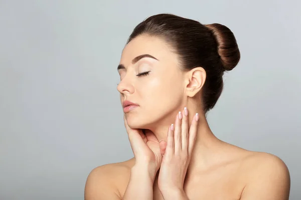 Mooie jonge vrouw met een zijdezachte huid na kuur op lichte achtergrond — Stockfoto