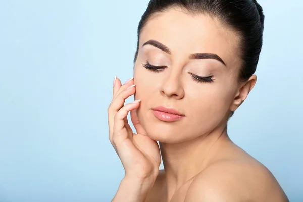 Mooie jonge vrouw met een zijdezachte huid na kuur op kleur achtergrond — Stockfoto