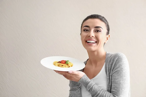 Mujer joven con plato de pasta sabrosa sobre fondo claro —  Fotos de Stock