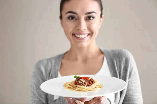 Mujer joven con plato de pasta sabrosa sobre fondo claro —  Fotos de Stock