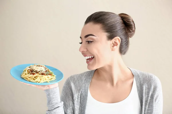 Mujer joven con plato de pasta sabrosa sobre fondo claro — Foto de Stock