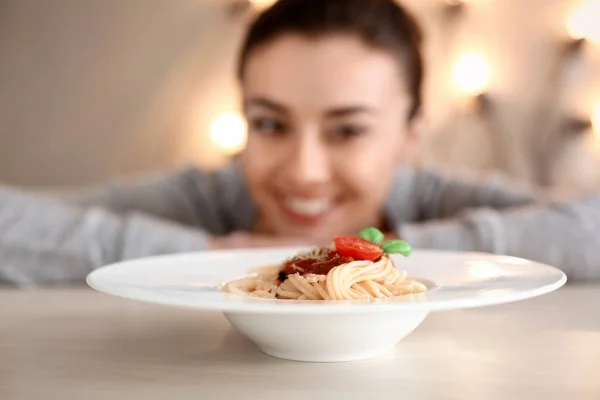 Piatto con gustosa pasta e donna sfocata sullo sfondo — Foto Stock