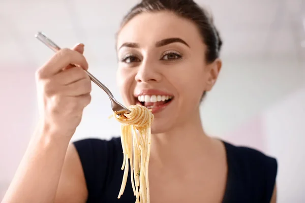 Young woman eating tasty pasta in restaurant — Stock Photo, Image