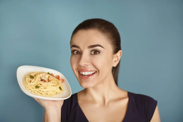 Mujer joven con plato de pasta sabrosa sobre fondo de color —  Fotos de Stock