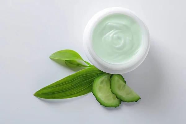 Body cream and cucumber slices on white background — Stock Photo, Image