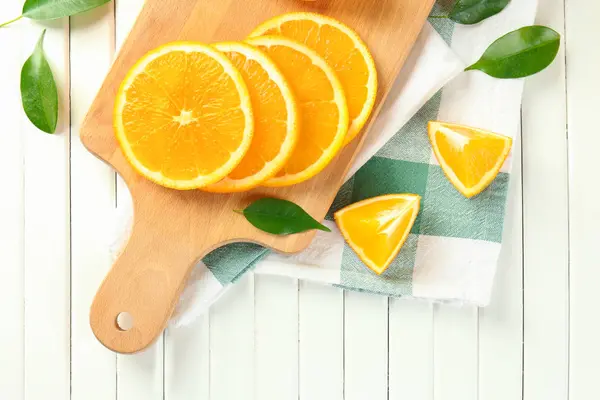 Placa de madeira com laranjas saborosas de corte na mesa — Fotografia de Stock