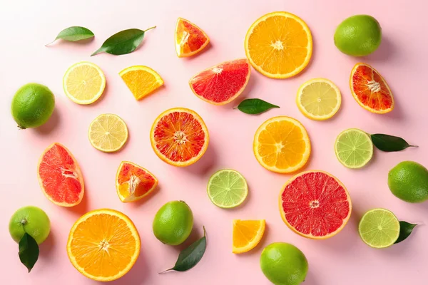 Different cut citrus fruits on color background, top view — Stock Photo, Image