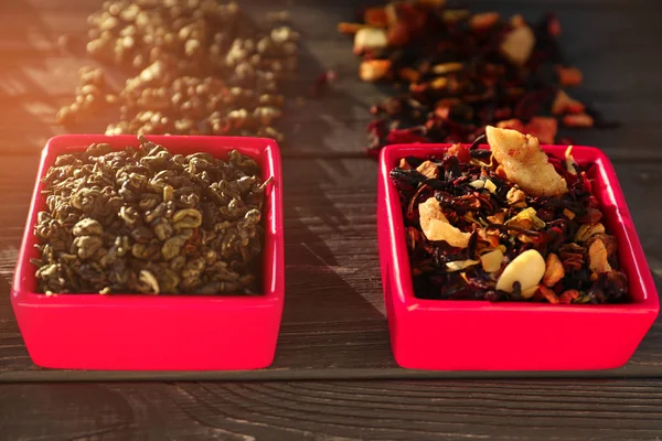 Bowls with different types of dry tea leaves on wooden background — Stock Photo, Image