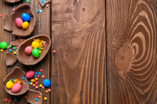 Huevos de Pascua de chocolate con caramelos y espolvoreos sobre fondo de madera, vista superior — Foto de Stock