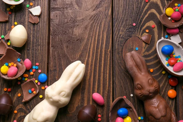 Hermosa composición de Pascua con conejitos de chocolate, huevos y caramelos sobre fondo de madera, vista superior — Foto de Stock