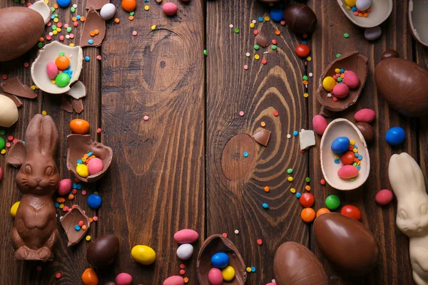 Hermosa composición de Pascua con conejitos de chocolate, huevos y caramelos sobre fondo de madera, vista superior — Foto de Stock