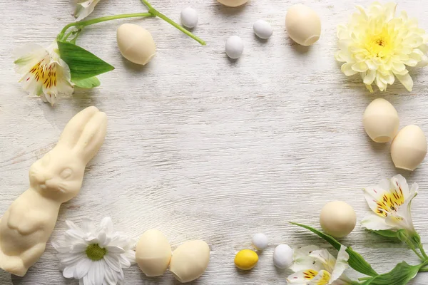 Beautiful Easter composition with chocolate bunny, eggs and flowers on wooden background, top view — Stock Photo, Image