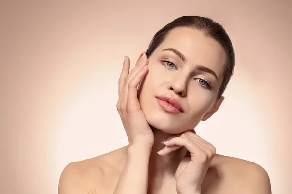 Mooie jonge vrouw met natuurlijke make-up op kleur achtergrond — Stockfoto