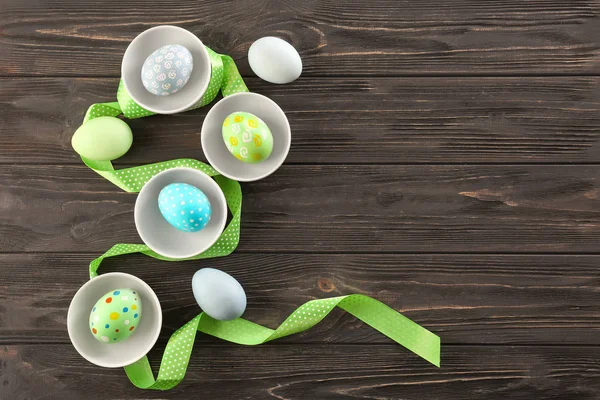 Bowls with colorful Easter eggs on wooden background — Stock Photo, Image